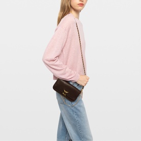 Model carrying Zadig brown crossbody bag with gold chain strap, styled with pink jumper and light blue jeans