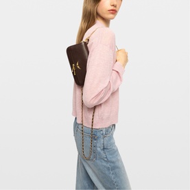 Model carrying Zadig brown crossbody bag with gold-tone chain strap, styled with a pink knit top and light blue jeans.