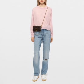 Model carrying Zadig brown crossbody bag with gold hardware, styled with pink sweatshirt, ripped light-wash jeans and white trainers