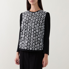 Model wearing Caroline Kilkenny top in white and black floral geometric print front panel with plain black long sleeves and crew neck.