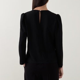 Model wearing Caroline Kilkenny top in black, back view, featuring keyhole neckline detail and structured puff shoulders, long sleeves.