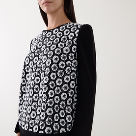 Model wearing Caroline Kilkenny top in white and black with geometric floral jacquard front panel and plain black long sleeves.