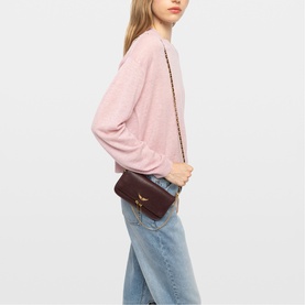 Model carrying Zadig purple crossbody bag with gold-tone chain strap, styled with pink jumper and light blue jeans