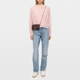 Model carrying Zadig purple crossbody bag with gold-tone hardware, styled with pink sweatshirt and light blue ripped jeans