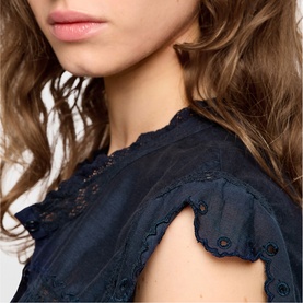Model wearing Zadig blue top with delicate broderie anglaise detailing and scalloped flutter sleeves, close-up view