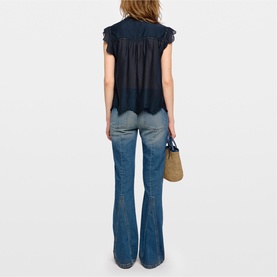Model wearing Zadig blue sleeveless top with ruffle trim and lace hem, styled with flared jeans; rear view