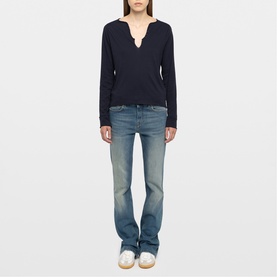 Model wearing Zadig blue long-sleeve notch-neck top with light wash flared jeans and white trainers