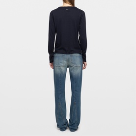 Model wearing Zadig blue long-sleeve top, back view, styled with mid-wash flared jeans