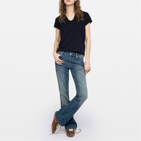 Model wearing Zadig blue jeans with a navy V-neck T-shirt and tan lace-up shoes, full-length relaxed fit style.
