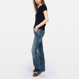 Model wearing Zadig blue flared jeans with black short-sleeve top and brown shoes, side profile view