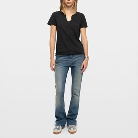 Model wearing Zadig green short-sleeve notch-neck T-shirt, styled with blue wash bootcut jeans and grey trainers.