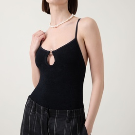 Model wearing Hunza G Toni Textured One-Piece Swimsuit in Metallic Rosewood with gold-tone ring hardware and narrow straps, styled with pearl