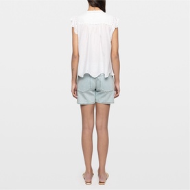 Model wearing Zadig white short-sleeve top with scalloped hem, styled with pale blue scalloped shorts and nude heeled mules