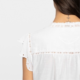 Model wearing Zadig white top, close-up of back neckline with lace trim and broderie anglaise detailing on short sleeves.