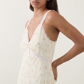 Model wearing LOVESHACKFANCY Lemon Haze floral viscose dress with V-neckline, lace trim, and adjustable straps, styled close-up side view.