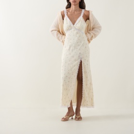Model wearing LOVESHACKFANCY Lemon Haze floral midi dress with front split, styled with a beige cardigan and strappy heeled sandals.