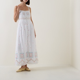 Model wearing LOVESHACKFANCY Optic White cotton maxi dress with floral embroidery, square neckline, and spaghetti straps, styled with cream flat