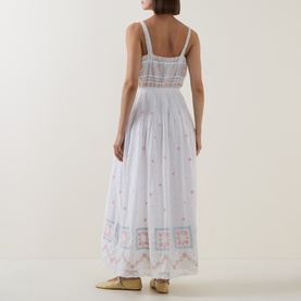 Model wearing LOVESHACKFANCY Optic White cotton maxi dress, back view, showing floral embroidery, lace trim inserts and square neckline straps.