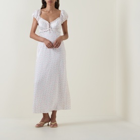 Model wearing LOVESHACKFANCY Ivory Rose dress with ruffle neckline, floral print, and midi length, styled with strappy heeled sandals.