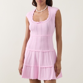 Model wearing LoveShackFancy Candy Floss Pink knit mini dress with tiered skirt and scoop neck, styled with pearl necklace