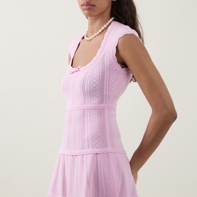 Model wearing LOVESHACKFANCY Candy Floss Pink knit dress with scoop neck and tiered skirt, styled with a pearl necklace