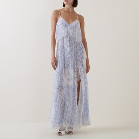 Model wearing LOVESHACKFANCY Indigo Shores silk maxi dress with floral print, spaghetti straps, tiered skirt and front split.