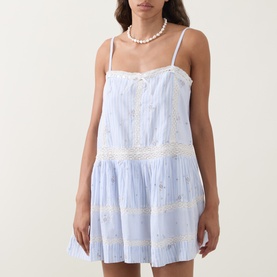 Model wearing LoveShackFancy Sky Mist blue striped cotton mini dress with lace trim detailing and thin straps, styled with pearl necklace