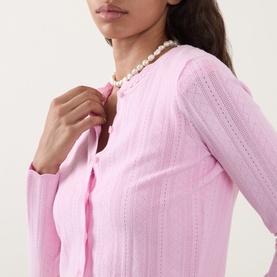 Model wearing LOVESHACKFANCY Candy Floss Pink pointelle knit top with pearl necklace, close-up detail shot showing ribbed texture.