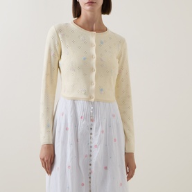 Model wearing LoveShackFancy Dayly cotton-cashmere cardigan with floral embroidery, styled with a white floral midi skirt.