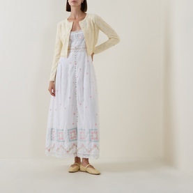 Model wearing LOVESHACKFANCY Dayly cotton cashmere cardigan, styled with white floral embroidered maxi dress and yellow ballet flats.