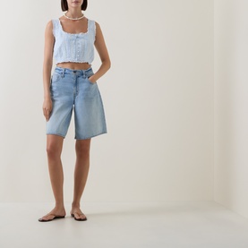 Model wearing LOVESHACKFANCY Blue Finch cotton crop top with square neck and button front, styled with light-wash denim shorts and flat sandals.