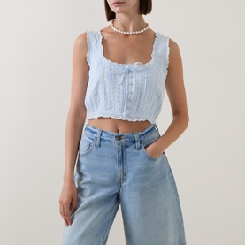 Model wearing LOVESHACKFANCY Blue Finch cotton crop top with lace trim and button front, styled with light wash wide-leg jeans and pearl necklace.