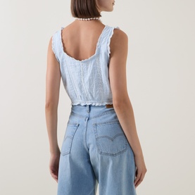 Model wearing LOVESHACKFANCY Blue Finch cotton crop top, back view, with ruffle trim and open back, styled with light-wash Levi's jeans and pearl