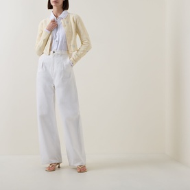 Model wearing LOVESHACKFANCY Optic White linen top, styled with cream cropped jacket and wide-leg white trousers.