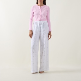 Model wearing LOVESHACKFANCY Optic White linen trousers with floral embroidery, wide-leg fit, styled with a pink cropped cardigan.