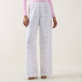 Model wearing LOVESHACKFANCY Optic White wide-leg linen trousers with floral embroidery, styled with a pink long-sleeve top.