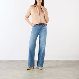 Model wearing LAgence Soft Nude silk blouse with wide-leg blue jeans and tan heeled mules.