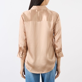 Model wearing L'Agence Soft Nude silk blouse, back view, with three-quarter roll-tab sleeves, styled with blue jeans.