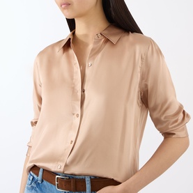 Model wearing L'Agence Soft Nude silk blouse with pointed collar and button front, styled with blue jeans and brown belt.