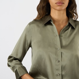 Model wearing L'Agence Smokey Olive 100% silk blouse with point collar, button front, and rolled cuffs, cropped close-up view.