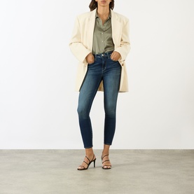 Model wearing LAgence Smokey Olive silk blouse, styled with cream blazer and dark blue skinny jeans, paired with black strappy heels.