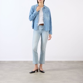 Model wearing LAgence Crop Boot jeans in light blue denim, styled with a chambray shirt, white tee and black mules.