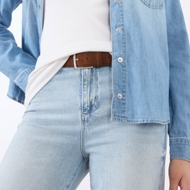 Model wearing LAgence Crop Boot jeans in light blue denim, styled with a denim shirt, white tee and brown leather belt.