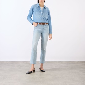 Model wearing LAgence Crop Boot jeans in light blue denim, styled with a chambray shirt and brown belt