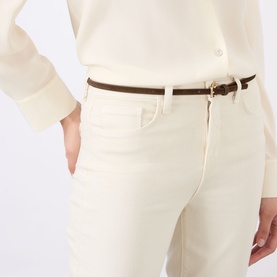 Model wearing LAgence Vintage White flare jeans, styled with a dark brown belt and cream top. High-rise waist, cotton-blend denim.