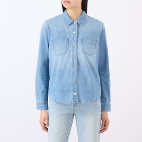 Model wearing L'Agence blue denim shirt with chest pockets and snap buttons, styled with light blue jeans