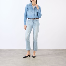 Model wearing LAgence blue cotton shirt with light wash cropped flare jeans, brown belt and black slingback heels.