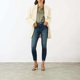Model wearing LAgence dark blue skinny jeans, styled with a cream blazer, khaki shirt and black strappy heeled sandals.
