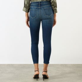 Model wearing LAgence dark blue skinny jeans, rear view, shown with a khaki shirt and black heeled mules.