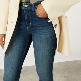 Model wearing L'Agence dark blue skinny jeans with high waist, styled with a cream blazer